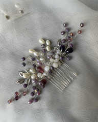 A comb pin with black and white crystals and rhinestones, displayed on a fabric surface.