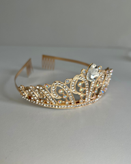 Gold tiara with a central gemstone on a white background.