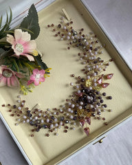 A hair accessory displayed in a case, featuring pearls and other decorative elements.