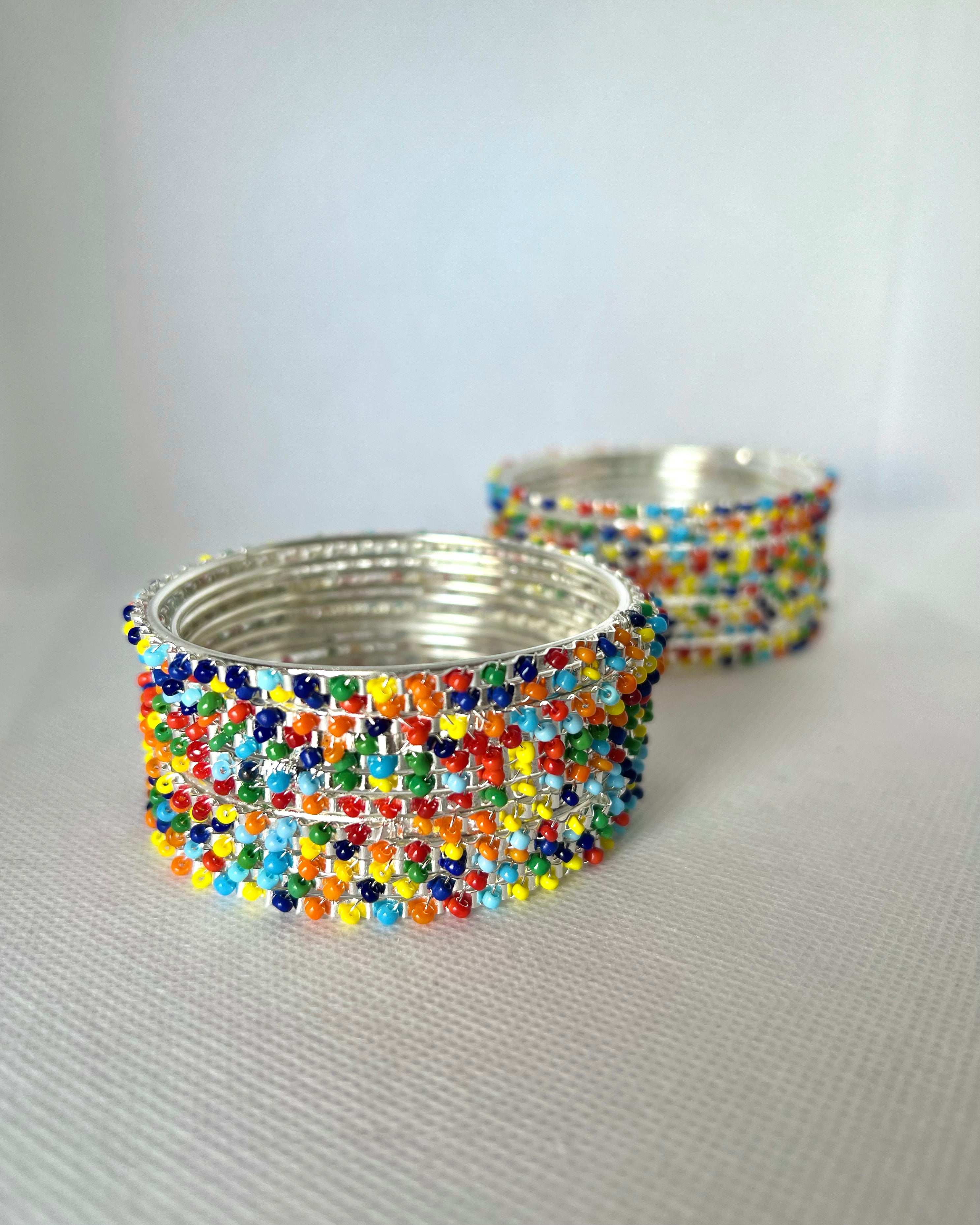 A set of multicolor beaded bangles with a silver metal frame, displayed in a 2x6 layout.