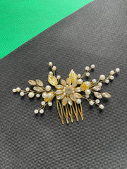 Decorative hair comb with pearls and gold leaves on a gray background