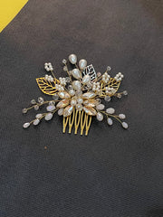 Decorative hair comb with pearls and gold leaves on a dark background