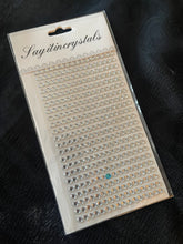 Packaged crystal embellishments with 'Sayitincrystals' branding on a dark background