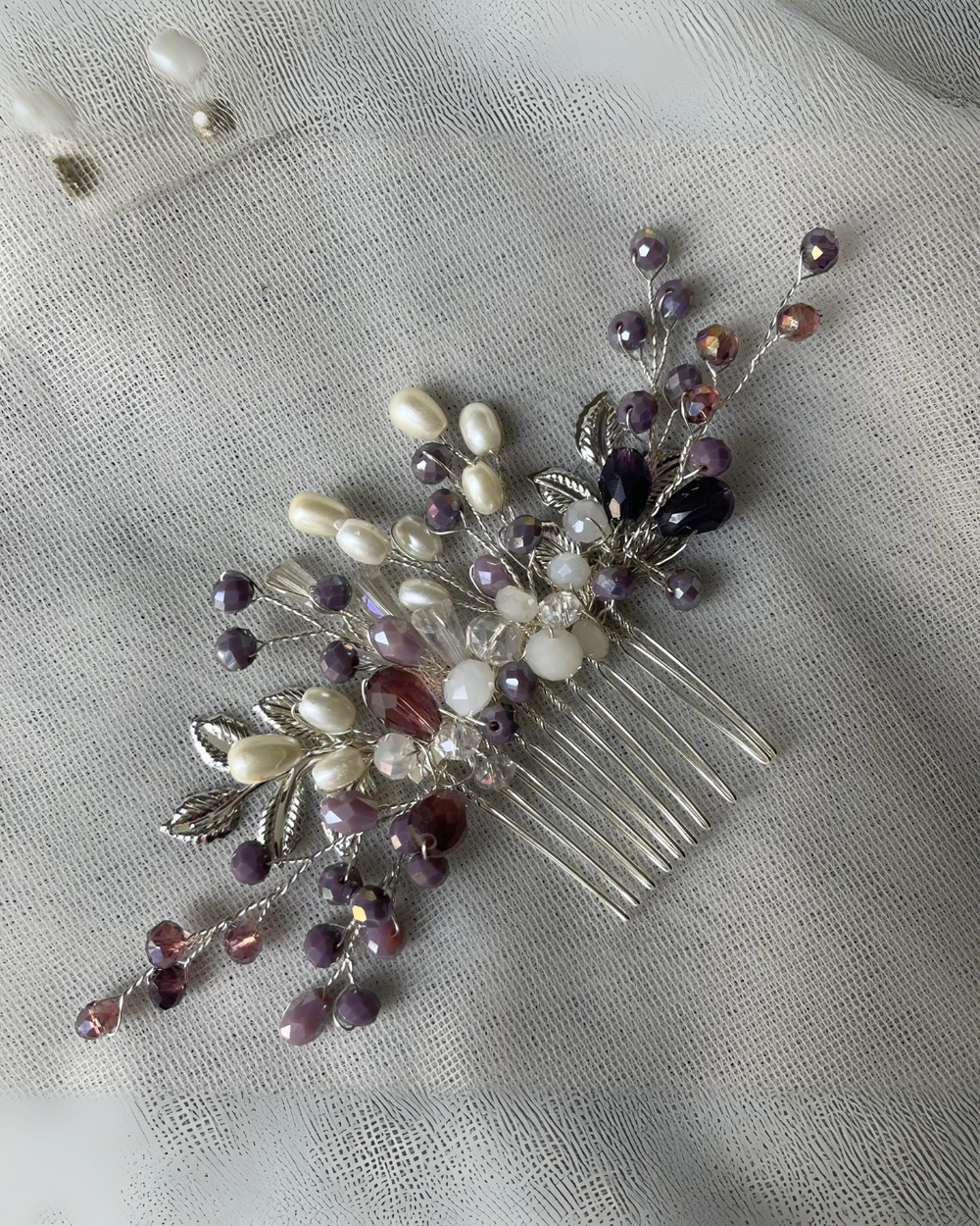 A comb pin with black and white crystals and rhinestones, displayed on a fabric surface.