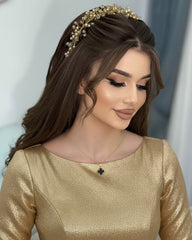 Woman wearing a gold dress and headband against a neutral background