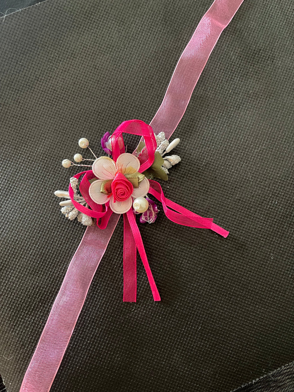 Floral corsage with pink ribbons on a dark background