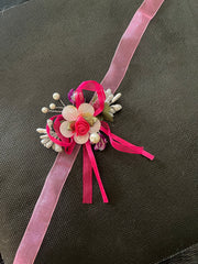Floral corsage with pink ribbons on a dark background