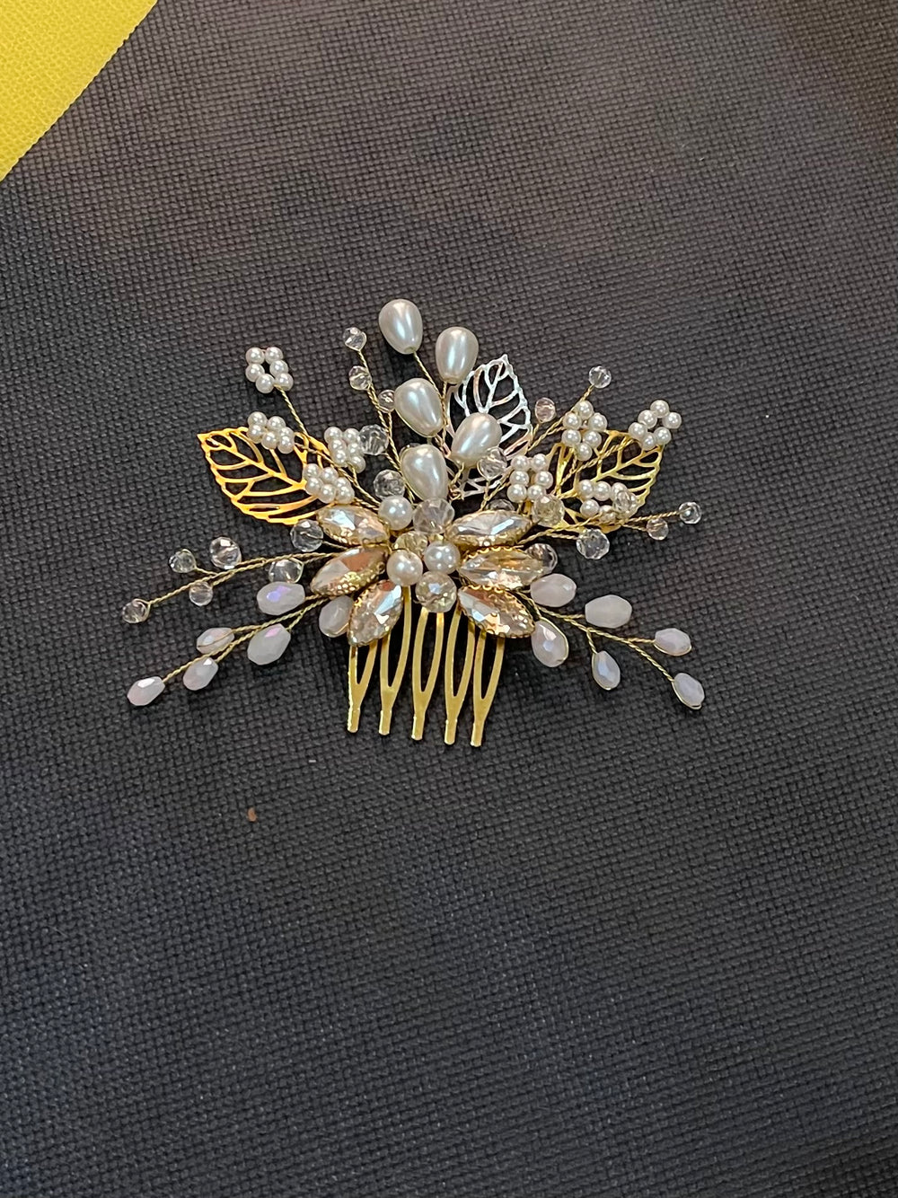 Decorative hair comb with pearls and gold leaves on a dark background