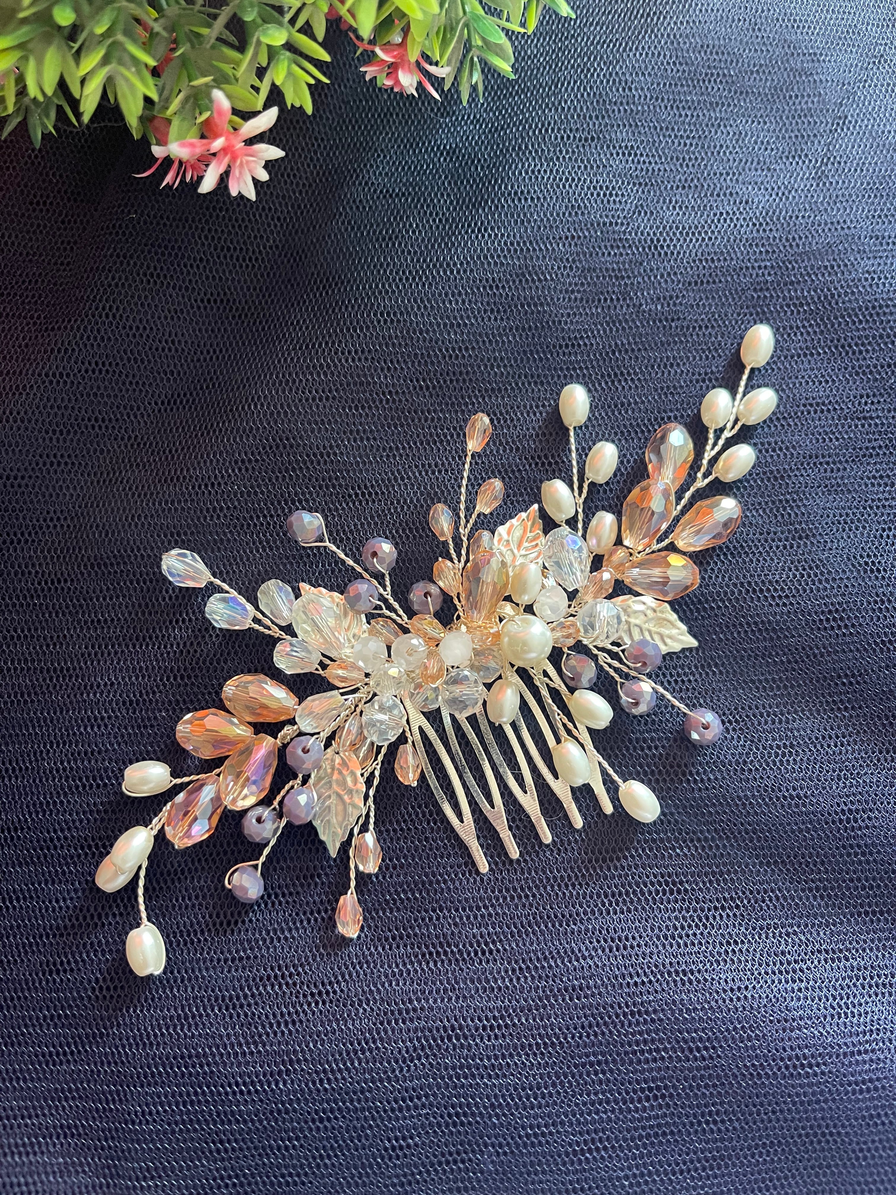 Decorative hair comb with beads and leaves on a dark fabric background