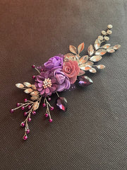 Decorative floral hair clip with purple and pink flowers on a brown background