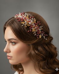 Woman wearing a decorative headpiece with red and gold elements on a gray background