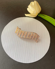 Gold beaded hair clip on a white round pad with a white tulip on a dark surface